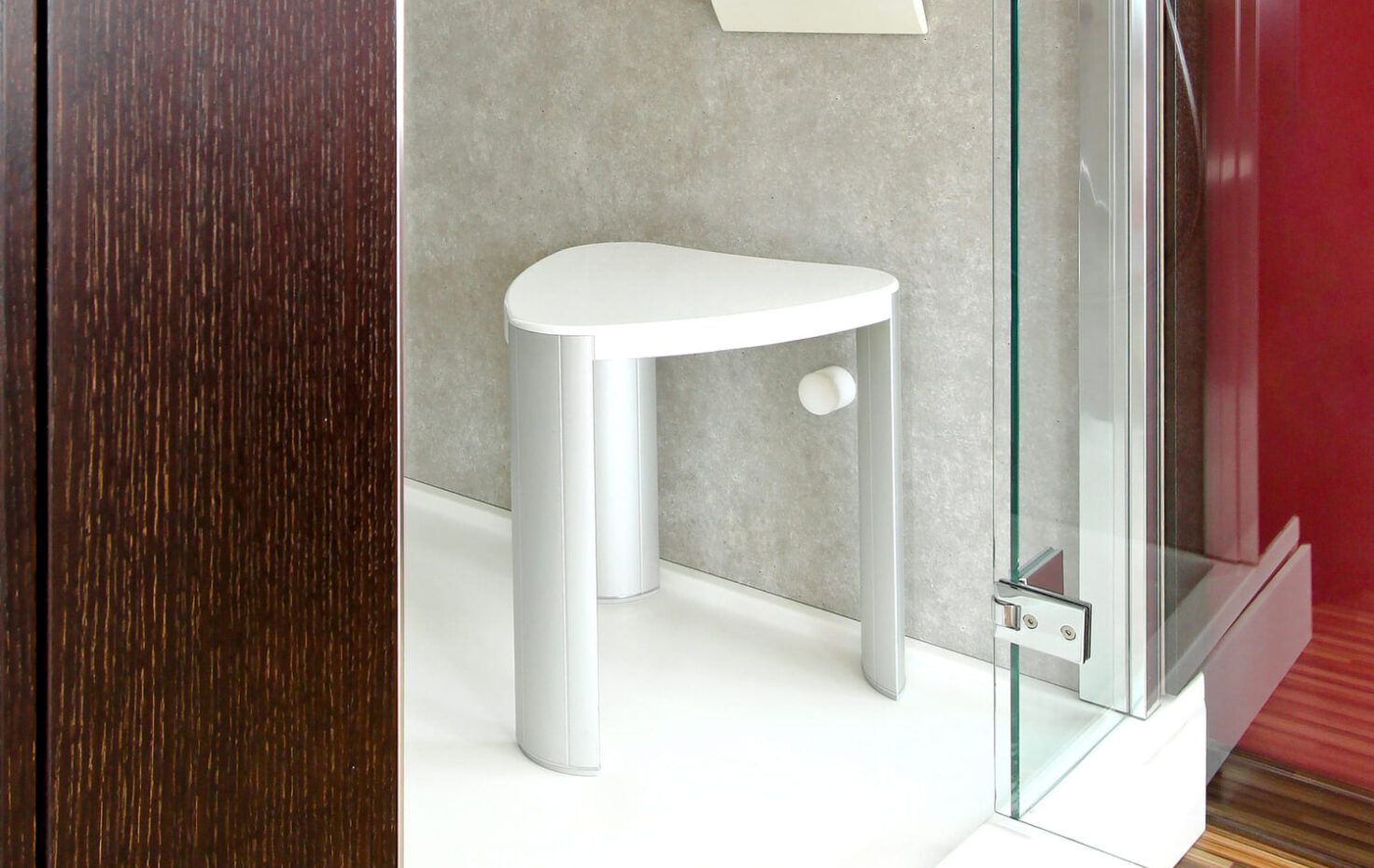 Ducha con mampara de cristal y taburete blanco para sentarse