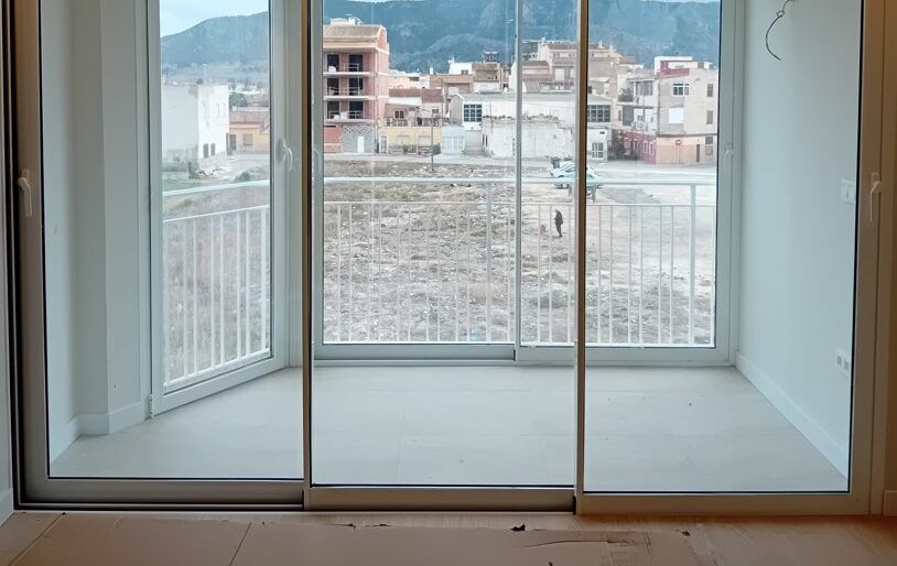 Puerta corredera blanca de tres hojas que da a un balcón, en un piso recién terminado