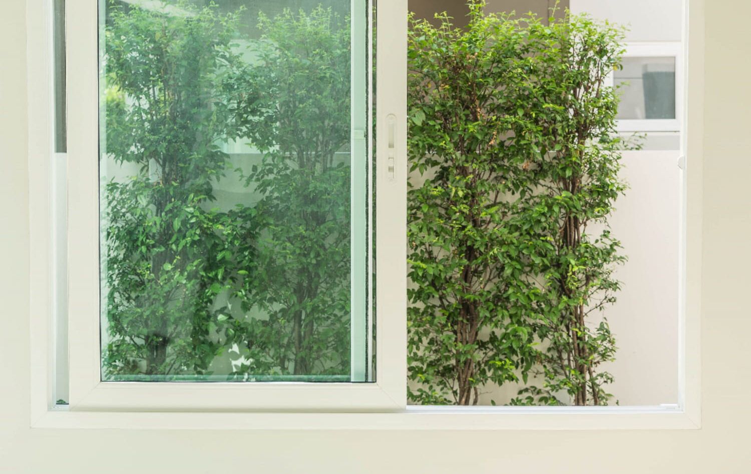 Ventana blanca abierta a un patio con plantas